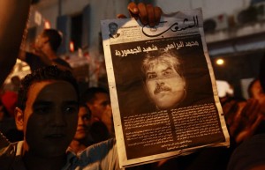 A demonstrator holds up a poster with an image of slain opposition figure Mohamed Brahimi to protest his assassination in Tunis