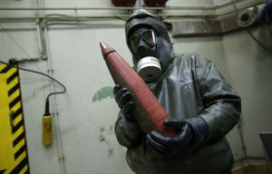 A worker dressed in protective clothing holds a dummy chemical grenade during a demonstration at GEKA  in Munster