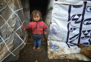 CHILD STANDS OUTSIDE MAKESHIFT SHELTER AT REFUGEE CAMP IN LEBANON